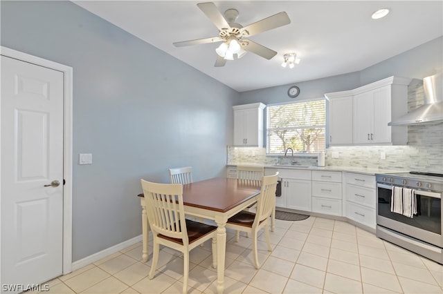 kitchen featuring white cabinets, stainless steel range oven, light tile floors, tasteful backsplash, and ceiling fan