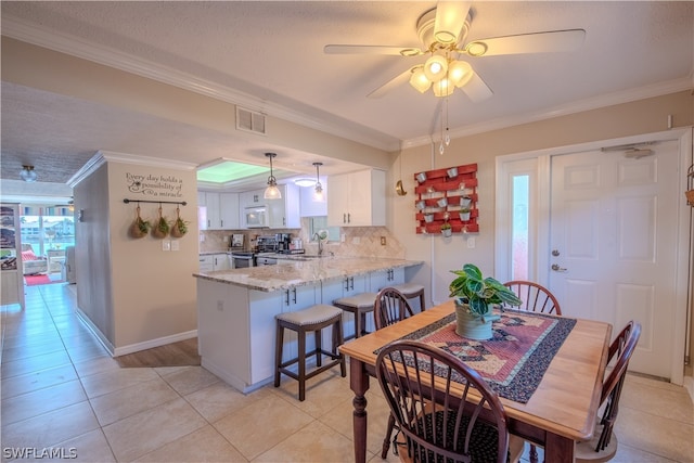 dining space featuring ceiling fan, crown molding, and light tile floors