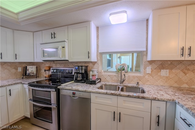 kitchen featuring double oven range, tasteful backsplash, white cabinets, sink, and stainless steel dishwasher