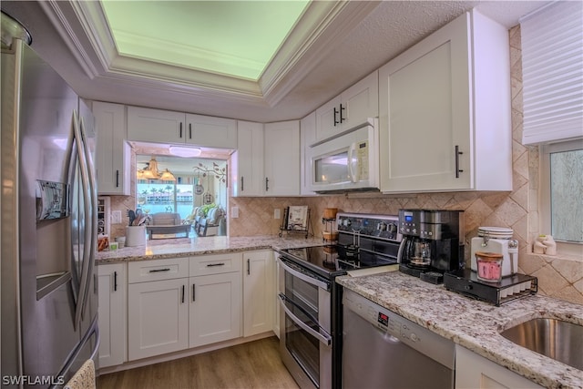 kitchen featuring light hardwood / wood-style flooring, tasteful backsplash, white cabinetry, and stainless steel appliances