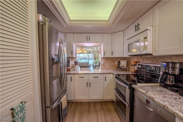 kitchen featuring light stone counters, stainless steel appliances, light hardwood / wood-style floors, and white cabinetry