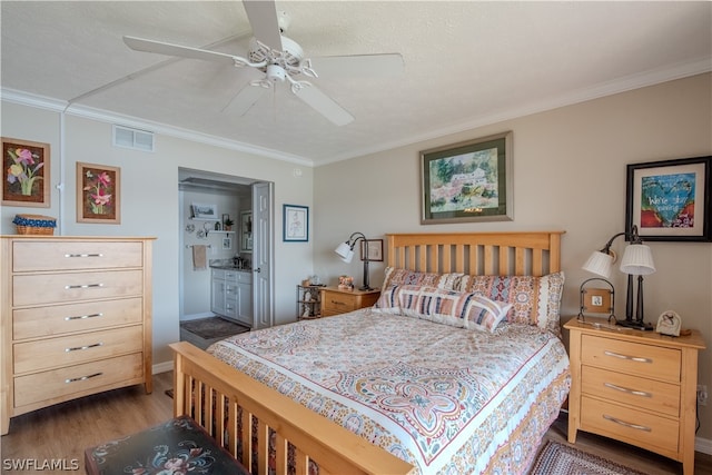 bedroom with crown molding, connected bathroom, ceiling fan, and dark hardwood / wood-style floors