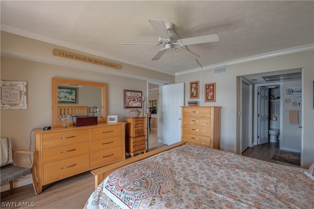 bedroom featuring hardwood / wood-style floors, ceiling fan, ensuite bath, and a textured ceiling