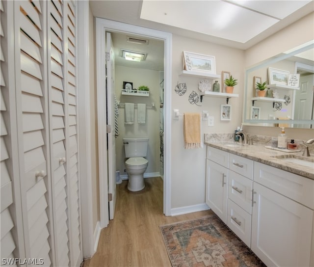 bathroom with vanity with extensive cabinet space, hardwood / wood-style flooring, toilet, and double sink