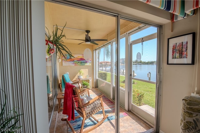 sunroom / solarium with ceiling fan, a water view, and a wealth of natural light