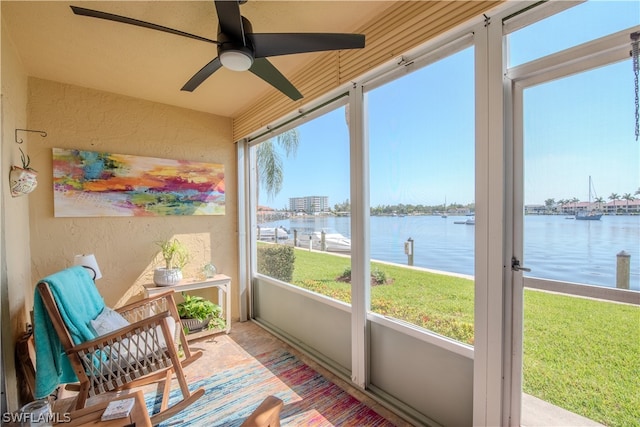 sunroom / solarium with ceiling fan and a water view