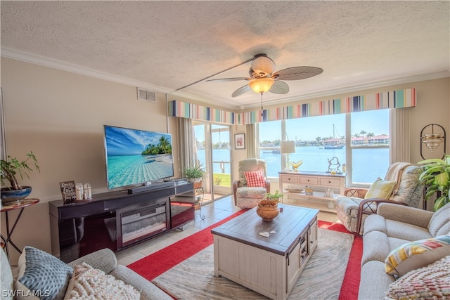 tiled living room with ornamental molding, ceiling fan, a textured ceiling, and a water view