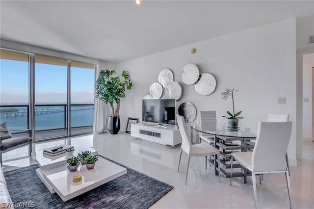 living room featuring a wall of windows, light tile floors, and a water view