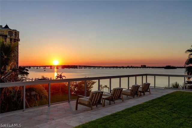 dock area featuring a patio area, a water view, and a lawn