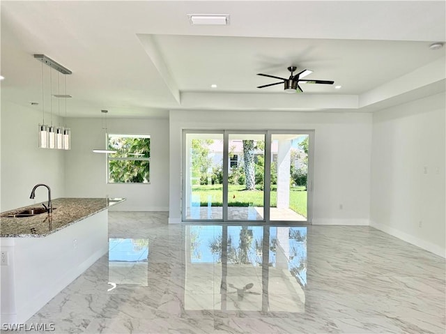 spare room with a tray ceiling, ceiling fan, and sink