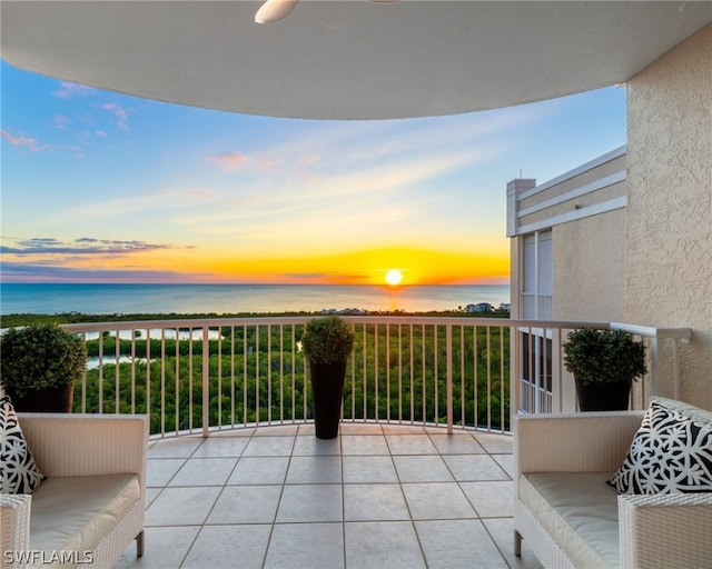 balcony at dusk featuring a water view