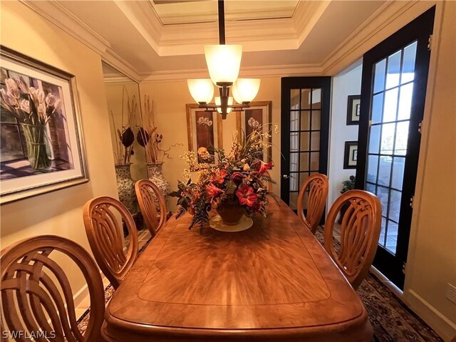 dining area with a notable chandelier, french doors, ornamental molding, and a tray ceiling