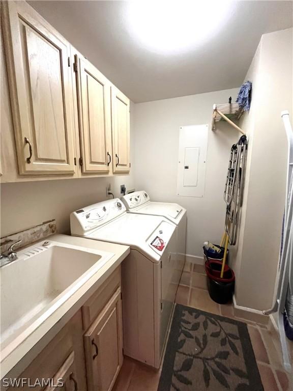 laundry room featuring washer and clothes dryer, sink, tile patterned flooring, cabinets, and electric panel