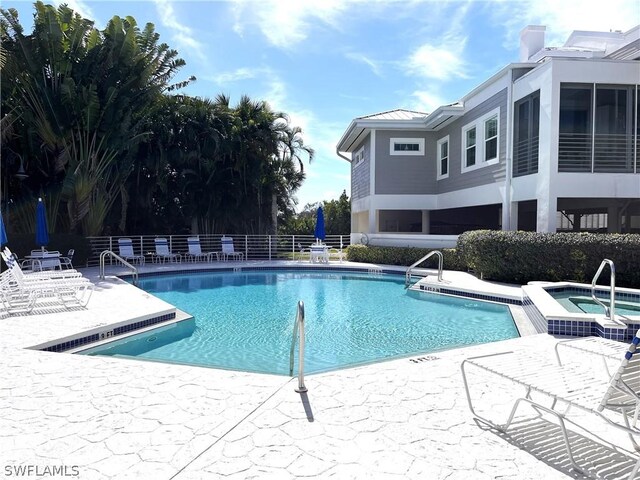 view of swimming pool featuring a hot tub and a patio area