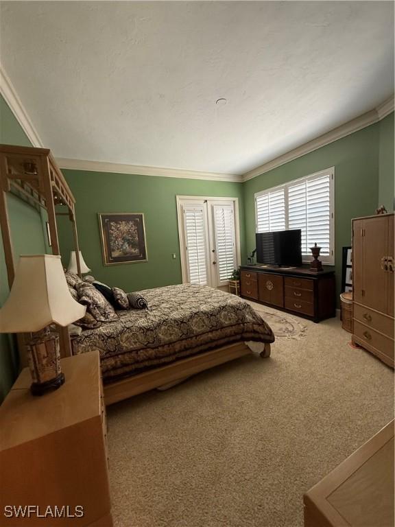 bedroom with ornamental molding and light carpet