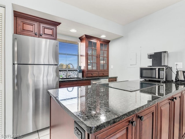 kitchen with sink, a kitchen island, stainless steel appliances, and dark stone counters