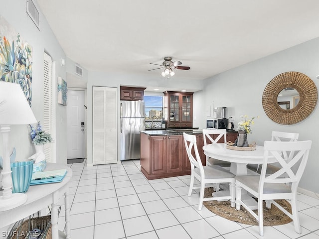 kitchen with appliances with stainless steel finishes, light tile flooring, and ceiling fan