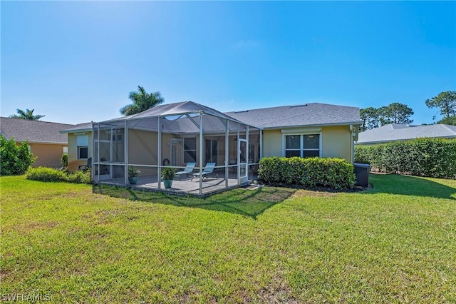 rear view of property featuring glass enclosure, a patio area, and a yard