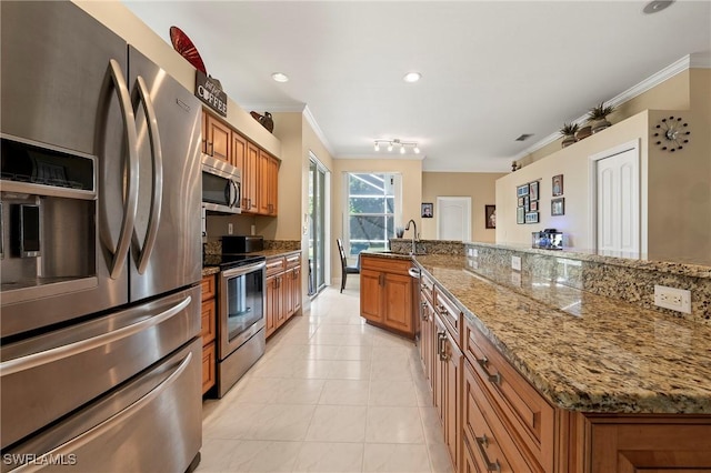 kitchen featuring a large island with sink, crown molding, appliances with stainless steel finishes, light tile patterned flooring, and light stone counters