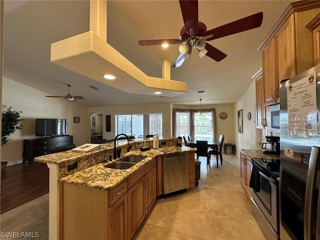 kitchen with sink, appliances with stainless steel finishes, ceiling fan, and stone counters