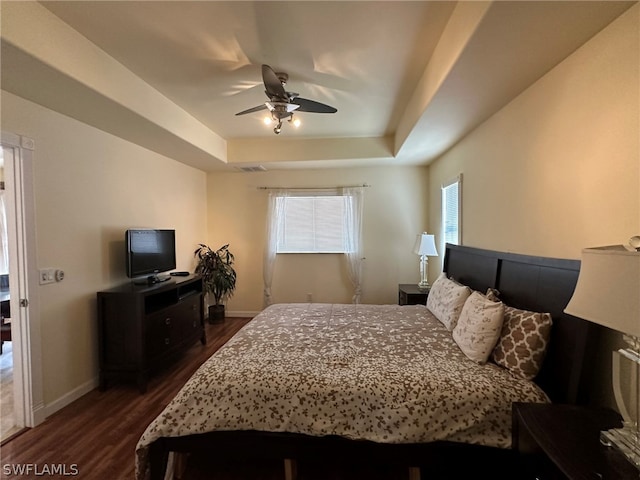 bedroom with ceiling fan, a raised ceiling, and dark hardwood / wood-style floors