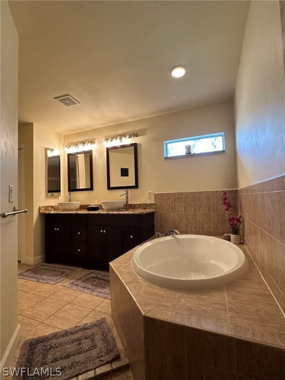 bathroom featuring a relaxing tiled bath, tile floors, and dual bowl vanity