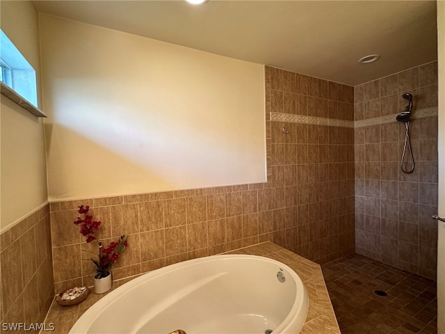 bathroom featuring independent shower and bath and tile walls