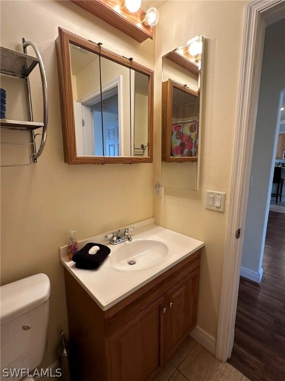 bathroom with hardwood / wood-style floors, vanity, and toilet