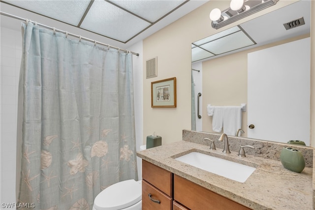 bathroom with a drop ceiling, vanity, toilet, and a shower with shower curtain