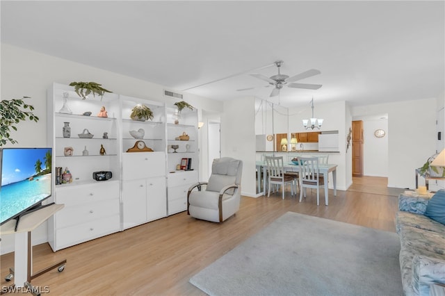 living room with light hardwood / wood-style floors and ceiling fan with notable chandelier