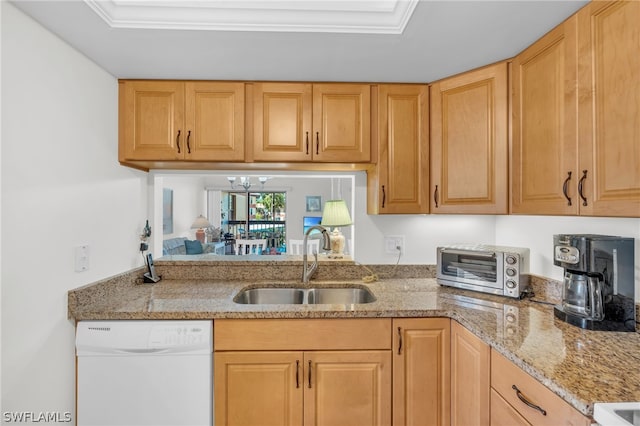 kitchen featuring sink, white dishwasher, light stone countertops, a tray ceiling, and a notable chandelier