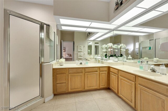 ensuite bathroom with a sink, a shower stall, and tile patterned flooring