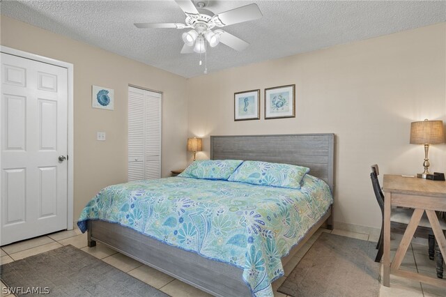 bedroom featuring light tile patterned floors, a textured ceiling, ceiling fan, and a closet