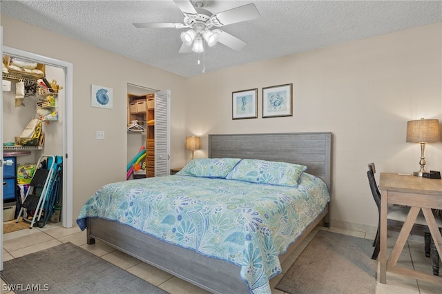 bedroom with ceiling fan, a spacious closet, a closet, and a textured ceiling