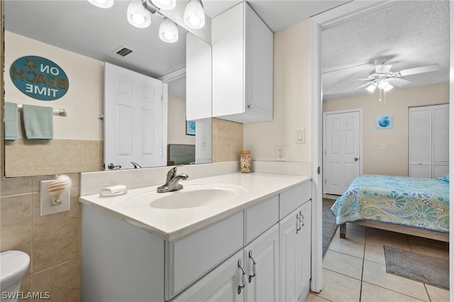 bathroom with ceiling fan, vanity, a textured ceiling, tile patterned floors, and toilet