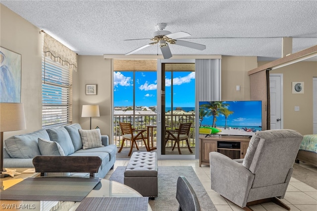 tiled living room with ceiling fan, a healthy amount of sunlight, and a textured ceiling