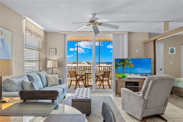 living room with ceiling fan, a textured ceiling, and light tile patterned floors