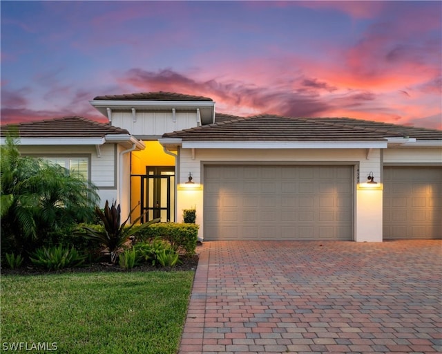 view of front of property featuring an attached garage, decorative driveway, and a tiled roof