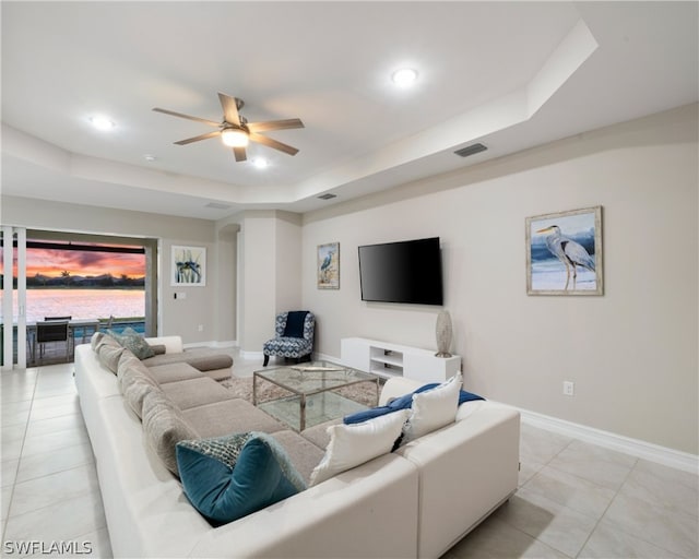 living room featuring a tray ceiling, recessed lighting, visible vents, and baseboards