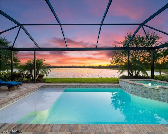 pool at dusk featuring a patio area, glass enclosure, and a water view