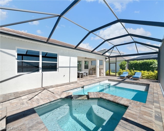 view of pool with glass enclosure, a pool with connected hot tub, ceiling fan, and a patio