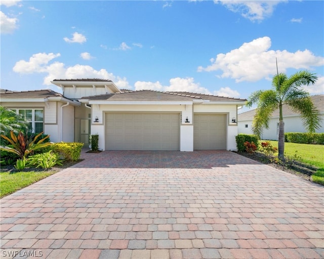 view of front of property with decorative driveway, a tile roof, an attached garage, and stucco siding