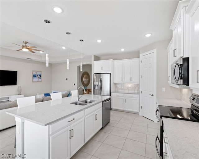 kitchen with stainless steel appliances, a sink, white cabinets, open floor plan, and an island with sink