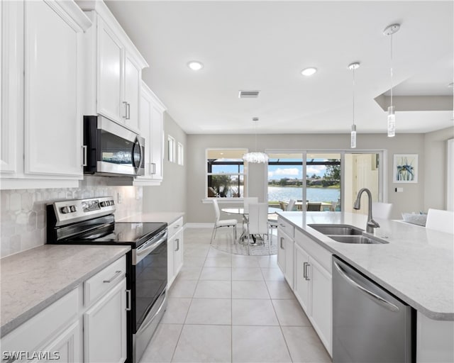 kitchen with pendant lighting, appliances with stainless steel finishes, a kitchen island with sink, white cabinetry, and a sink