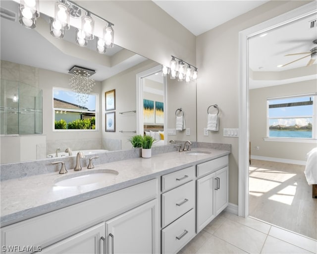 full bath featuring double vanity, tile patterned flooring, a raised ceiling, and a sink