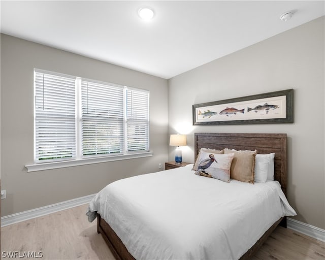 bedroom with light wood finished floors and baseboards