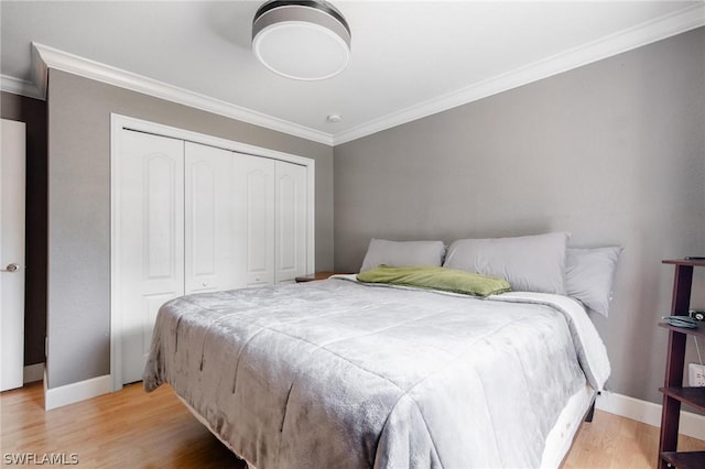 bedroom with light wood-type flooring, ornamental molding, and a closet