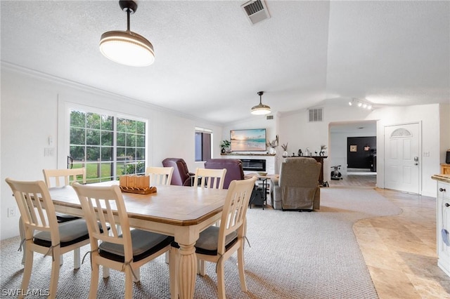 dining space with a textured ceiling, light colored carpet, vaulted ceiling, and ornamental molding