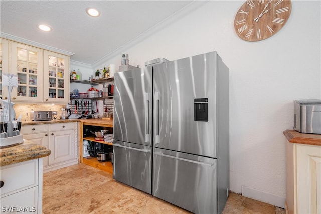 kitchen featuring tasteful backsplash, stainless steel fridge with ice dispenser, light stone counters, white cabinets, and ornamental molding