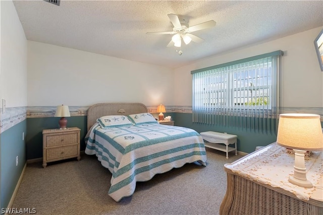 bedroom featuring ceiling fan, dark carpet, and a textured ceiling